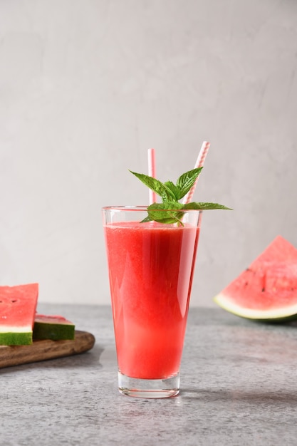 Watermelon summer cocktail garnish mint on grey background. Close up. Vertical format.