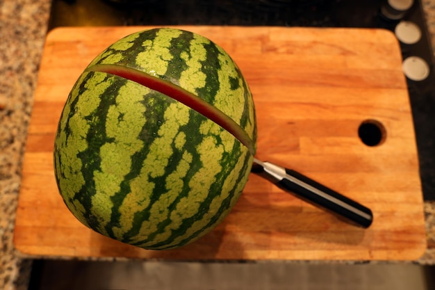 watermelon waiting to be cut with a chef039s knife on the counter board