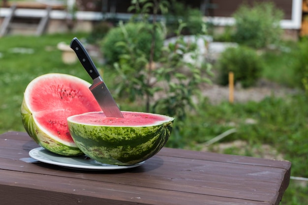 The watermelon was cut into two parts and a knife was inserted