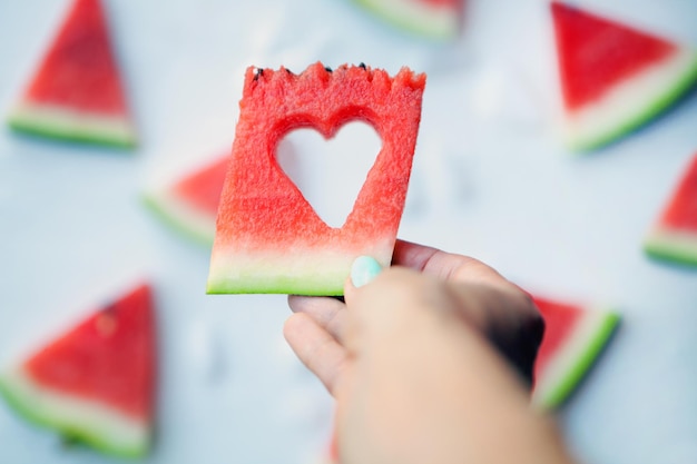 Watermelonhearts slices on womans hands Sliced watermelon on white background Flat lay top view Love and care concept