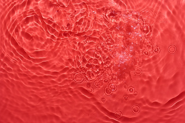 Wateroppervlak rood abstracte achtergrond Golven en rimpels textuur van cosmetische aqua hydraterende crème met bubbels