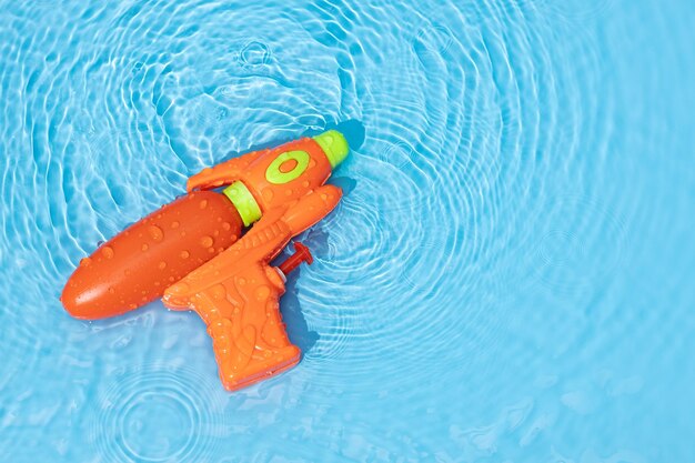 Foto waterpistool speelgoed op blauw water oppervlak met gerimpelde golven leuke vrije tijd zomer achtergrond kopieer ruimte
