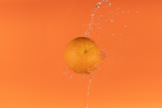 Waterplons op verse sinaasappel met bladeren die op oranje achtergrond worden geïsoleerd