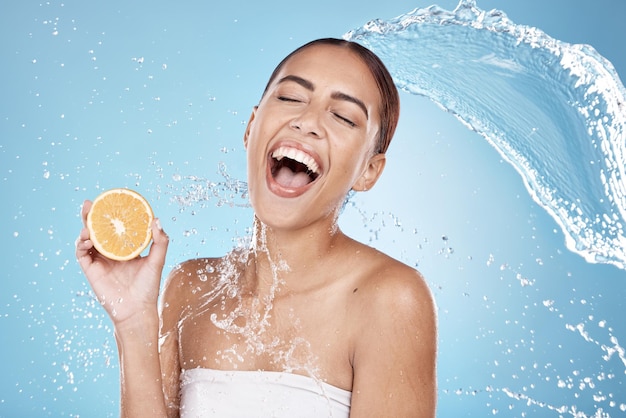 Waterplonsschoonheid en vrouw schoon met sinaasappel voor organische cosmetische zorg en hygiëne in douche Waterfruit en veganistische huidverzorgingsbehandeling met plons en opgewonden vrouw tegen studioachtergrond
