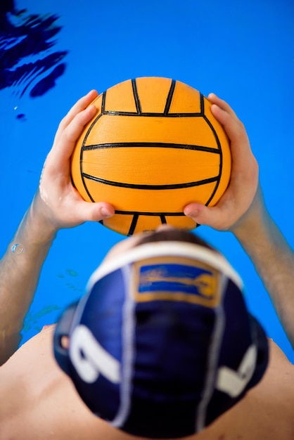 Foto waterpolotraining jonge sporter speelt waterpolo in het zwembad