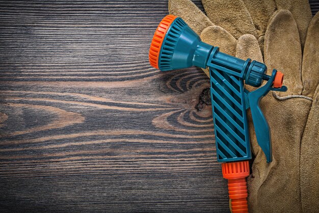 Watersproeier beschermende handschoenen op houten plank landbouw concept