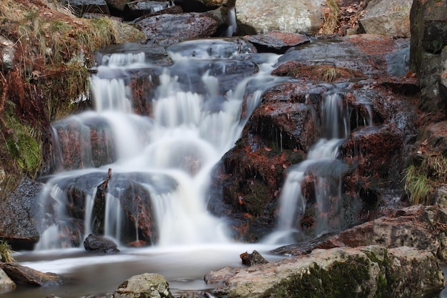 Waterval die in de herfst over de rotsen stroomt