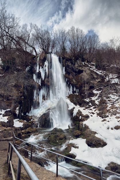 Waterval Gostilje, Servië in de winter. Sneeuw en ijs bedekte verborgen waterval in het bos in de winter.