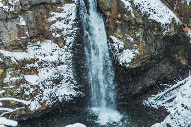 Waterval in besneeuwde bergen in de winter