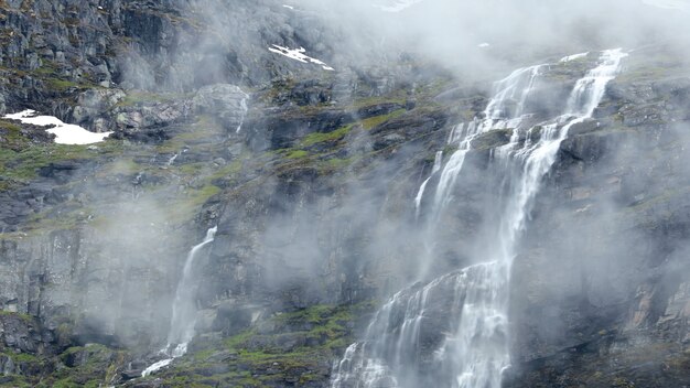 Waterval op de berghelling rotsen wolken mist sneeuw