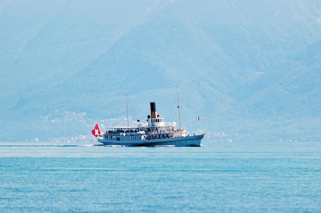 Waterveerbootschip met Zwitserse vlag in Meer Genève bij Ouchy-dijk, Lausanne, Zwitserland. mensen aan boord