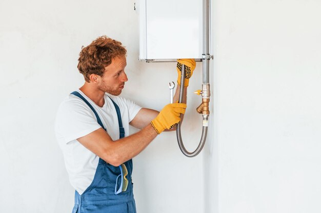 Waterverwarmer repareren Jonge man die overdag in uniform aan het werk is