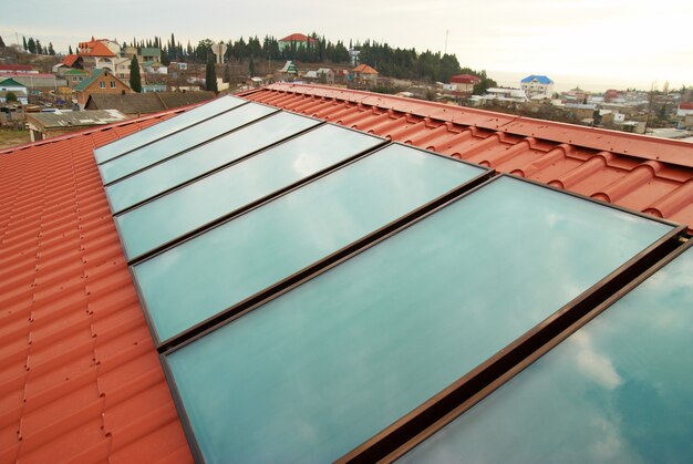 Waterverwarmingssysteem op zonne-energie (geliosysteem) op het rode huisdak.