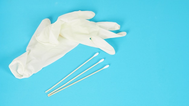 Wattenstaafjes voor wattenstaafjestest met witte medische handschoenen of latexhandschoen op blauwe achtergrond. covid-19 concept, geen mensen