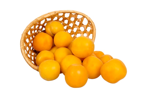 Плетеная корзина со спелыми желтыми абрикосами на белом фоне