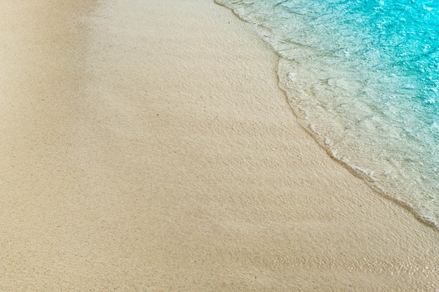 Wave of blue ocean on sandy beach with copy space