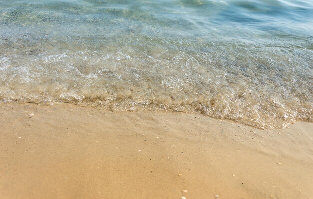 Wave of blue sea on sandy beach. Close up