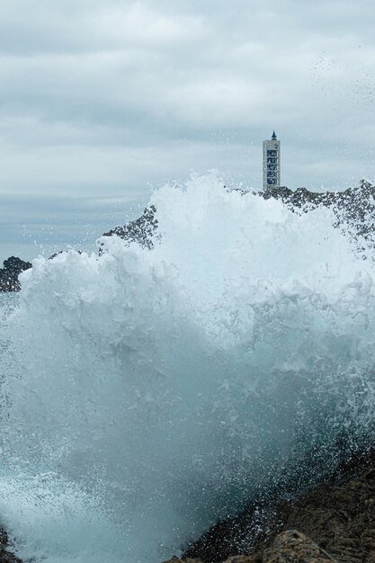 Wave breaking against the cliffs and forming a great curtain of foam at the Frouxeira lighthouse on the Galician coast