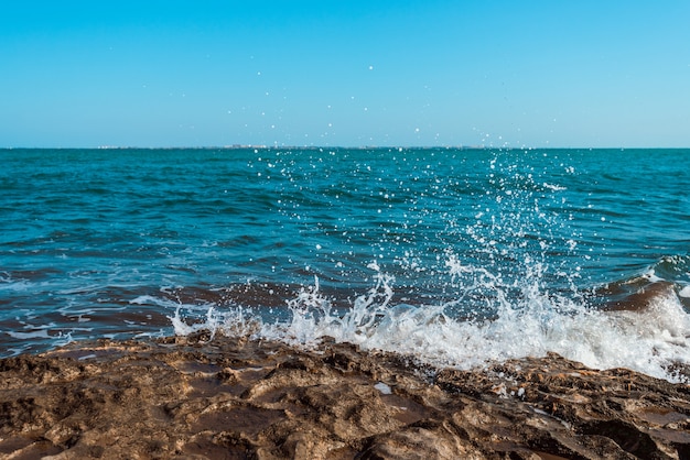 The wave breaks on the rock