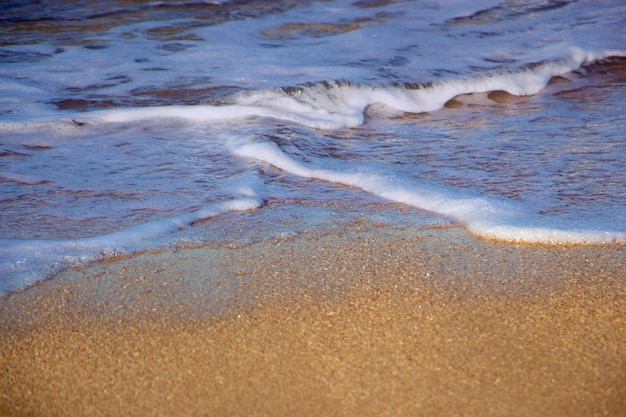 海の波の砂の背景に波と泡