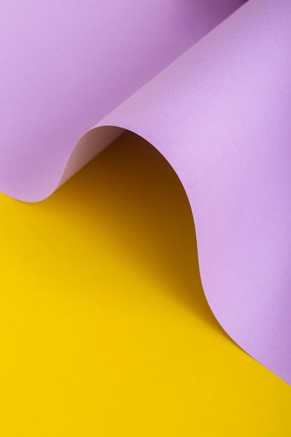 Wave from lilac cardboard on a yellow background. Top view, flat lay.