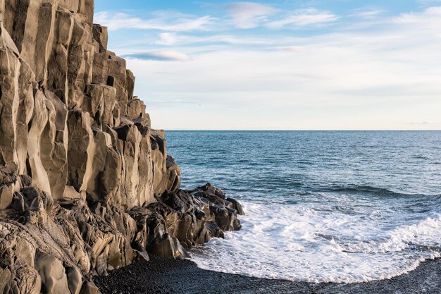 Wave hitting on Halsanefhellir cave with basalt rock formation on black sand beach in Reynisfjara beach