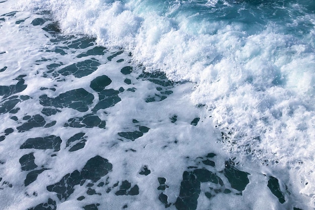Foto un'onda si infrange sulla riva di una spiaggia.