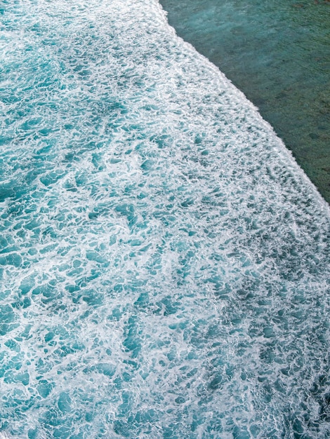 Foto un'onda si infrange sulla riva e il mare è blu.