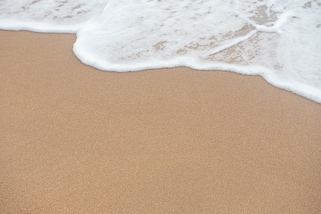 Foto priorità bassa della spiaggia di sabbia e dell'onda con lo spazio della copia.