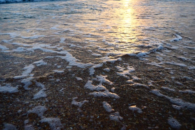 Wave and sunset over sea Beautiful sunset Foamy waves roll over the sandy shore Vityazevo Anapa Black Sea Tourist place health resort Evening sky The rays reflect off the water