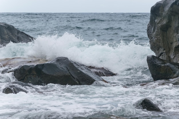 Waves are beating against rocks on the seashore the ocean in cloudy weather