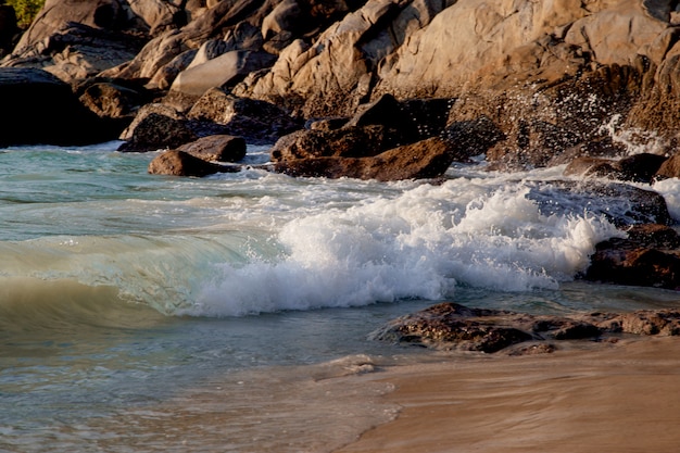 waves are breaking on stones on the ocean