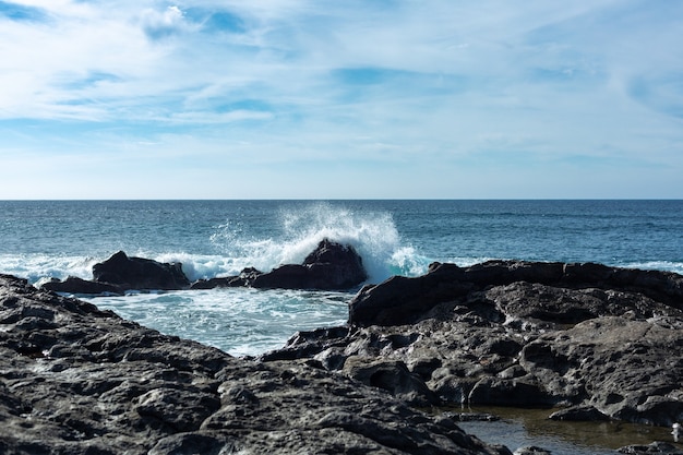 スペインのランサローテ島の冷やされた溶岩の周りに大西洋の波が飛び散っています。