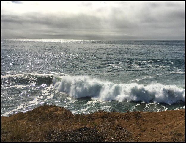 Foto le onde sulla spiaggia contro il cielo nuvoloso