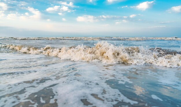 Le onde sulla spiaggia e il cielo blu con il paesaggio delle nuvole