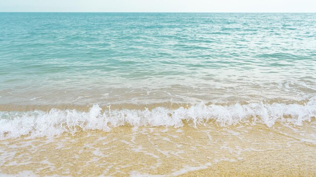 Foto le onde sulla spiaggia e l'acqua turchese dell'oceano in una soleggiata giornata estiva le onde si infrangono sulla spiaggia sabbiosa chiara il concetto di pulizia relax