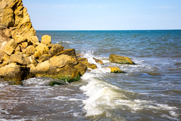 Waves beat against stones on a sunny day