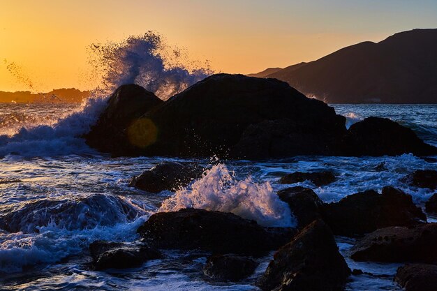 Le onde si infrangono sulle rocce durante il tramonto sulla costa occidentale