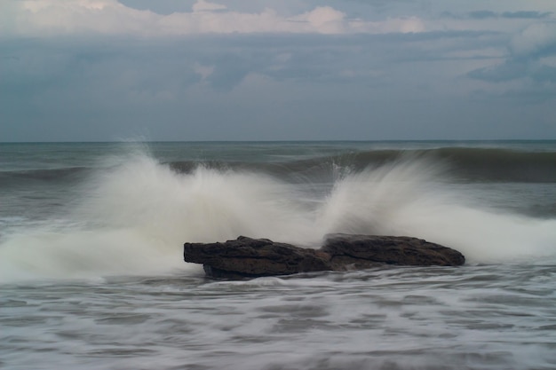 Waves crashing against the rocks on the beach during the day