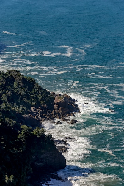 파도가 상파울루 북쪽 해안의 푸른 바다와 함께 해변에 충돌합니다. Sao Sebastiao, SP, 브라질