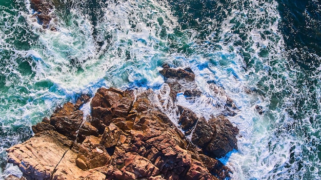 Waves crashing into rocky coasts of Maine aerial from above looking down