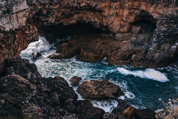 洞窟のある岩層の崖に打ち寄せる波