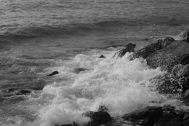 Photo waves crashing on the rocks in black and white