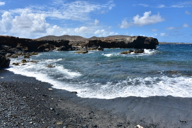 黒砂のビーチの海岸を優しく離れる波