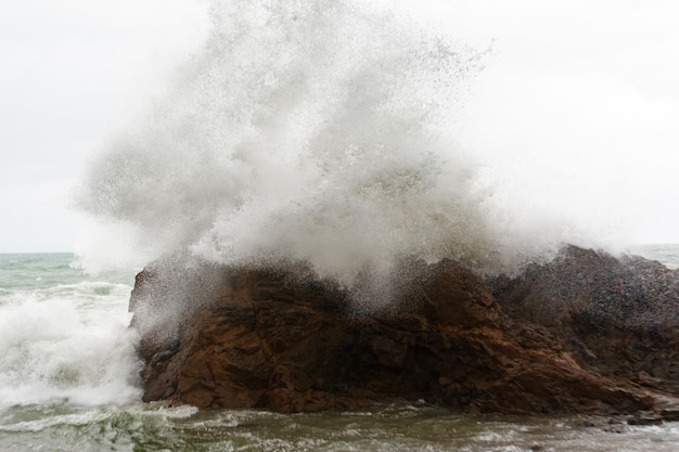 Фото Волны с большой силой бьются о морскую скалу.