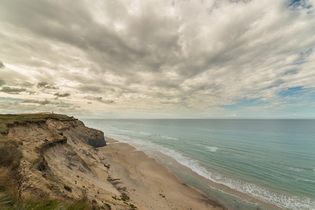 Waves of the ocean on the beach under the sky full of clouds