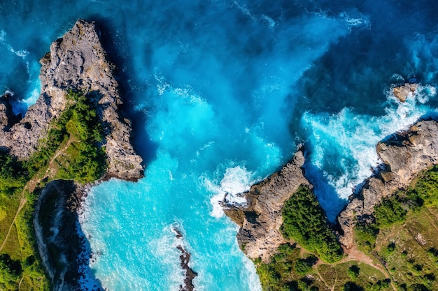 Onde e rocce come sfondo dalla vista dall'alto sfondo blu acqua dalla vista dall'alto paesaggio marino estivo dall'aria isola di bali indonesia