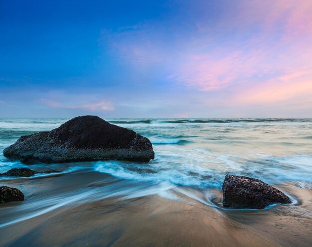 Waves and rocks on beach of sunset