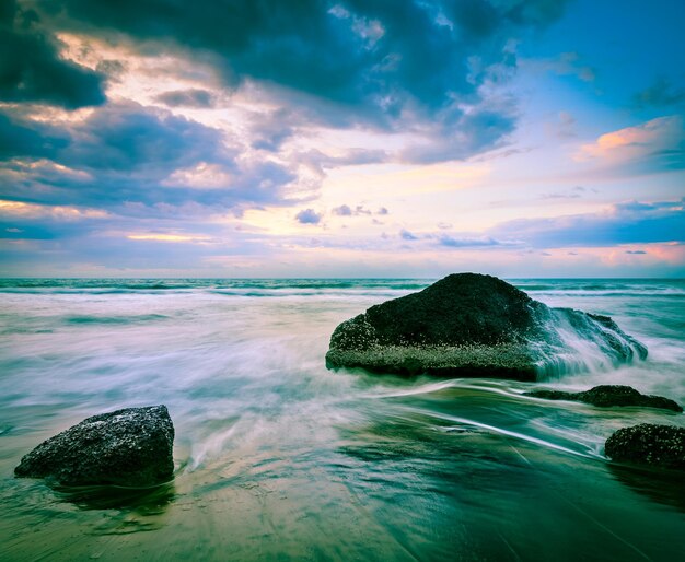 Waves and rocks on beach of sunset