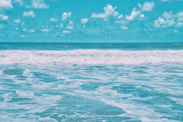 Photo waves rushing towards beach against cloudy sky